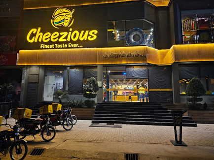Cheezious Neon-Lit Restaurant at Night Cheezious Crown Crust Pizza with cheesy crown edges and chicken toppings